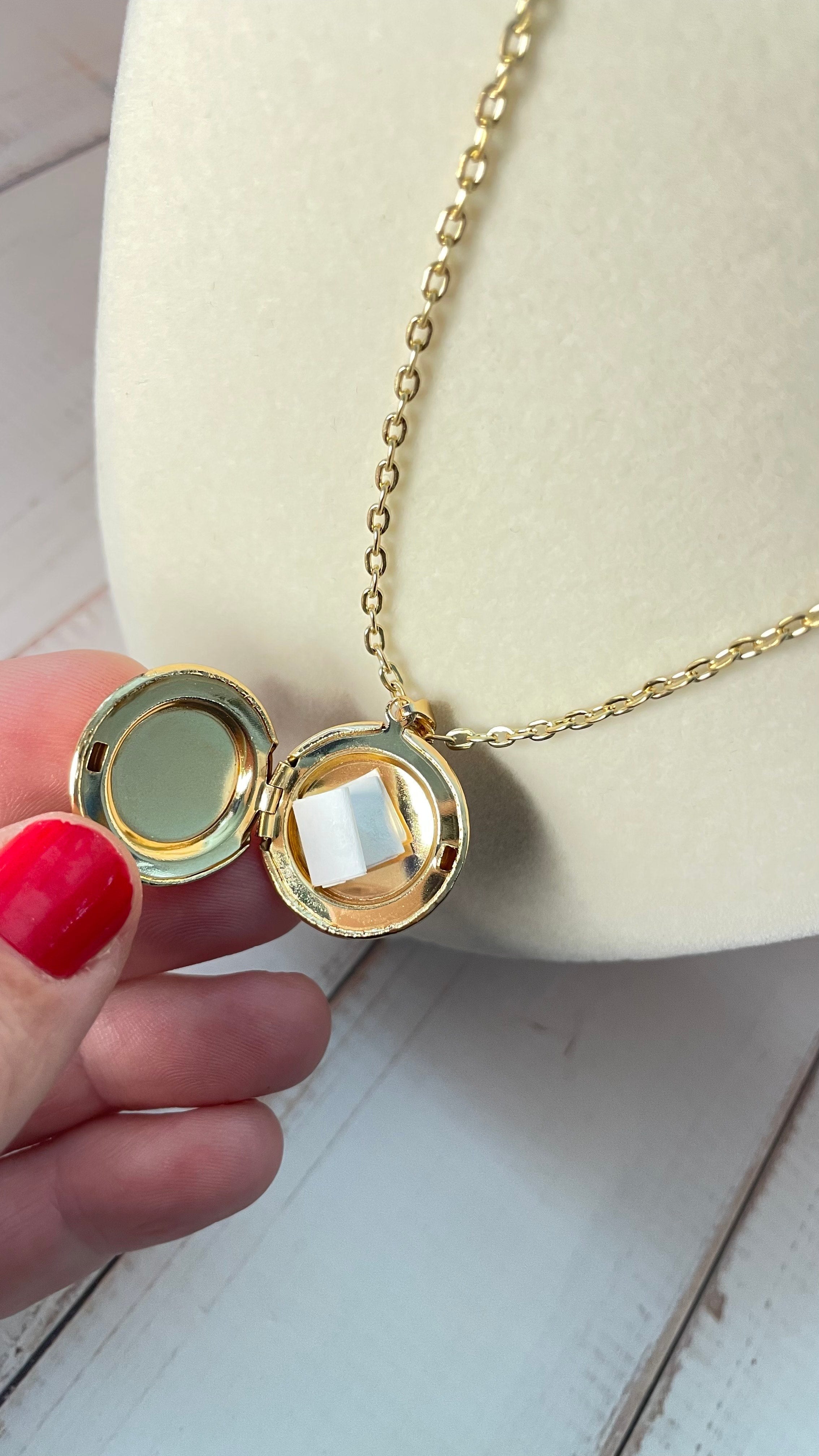 Open gold locket with a folded up paper inside that contains a secret message displayed on a mannequin bust